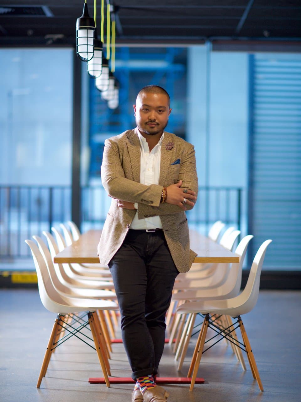 A marketing lead standing at the head of an empty meeting table in a dark office