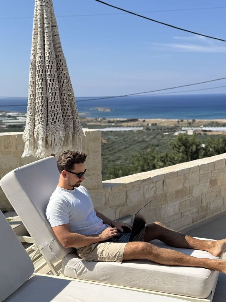Team member working on a laptop with the sea in view